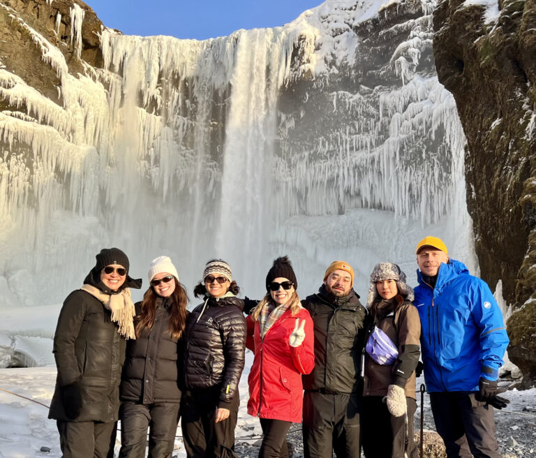 A group of tourists with a guide by the Skógafoss waterfall in Iceland in winter. Part of the South Coast Tour by Arctic Mike Iceland.