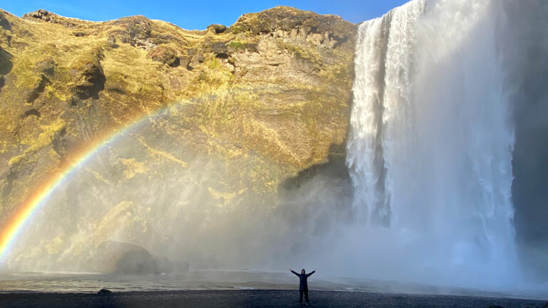 My guest by the Skógafoss waterfall in Iceland, with a rainbow. Part of the South Coast Tour by Arctic Mike Iceland.