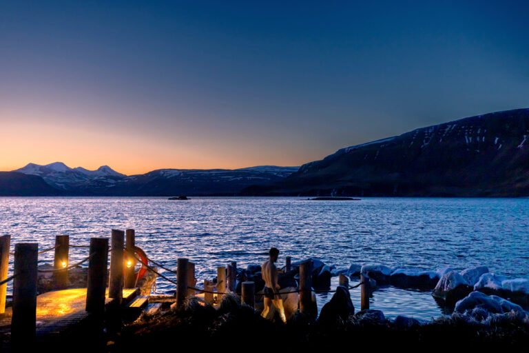 Picture of a man relaxing in the Hvammsvik hot spring at wintery sunset